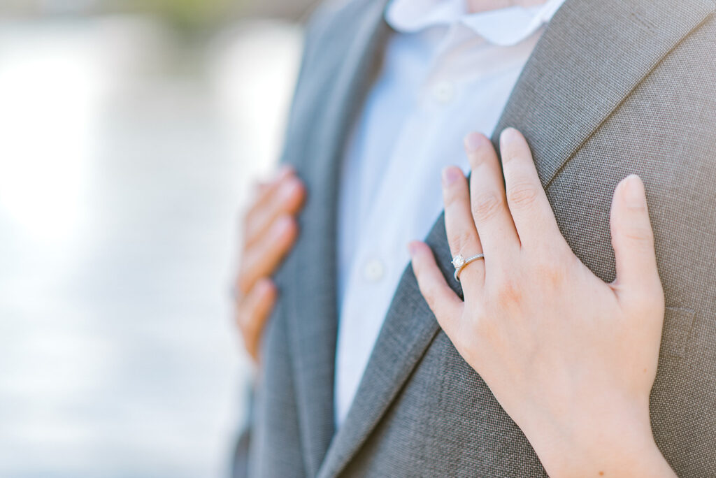 Woman's hands with engagement ring hugging gentleman from behind