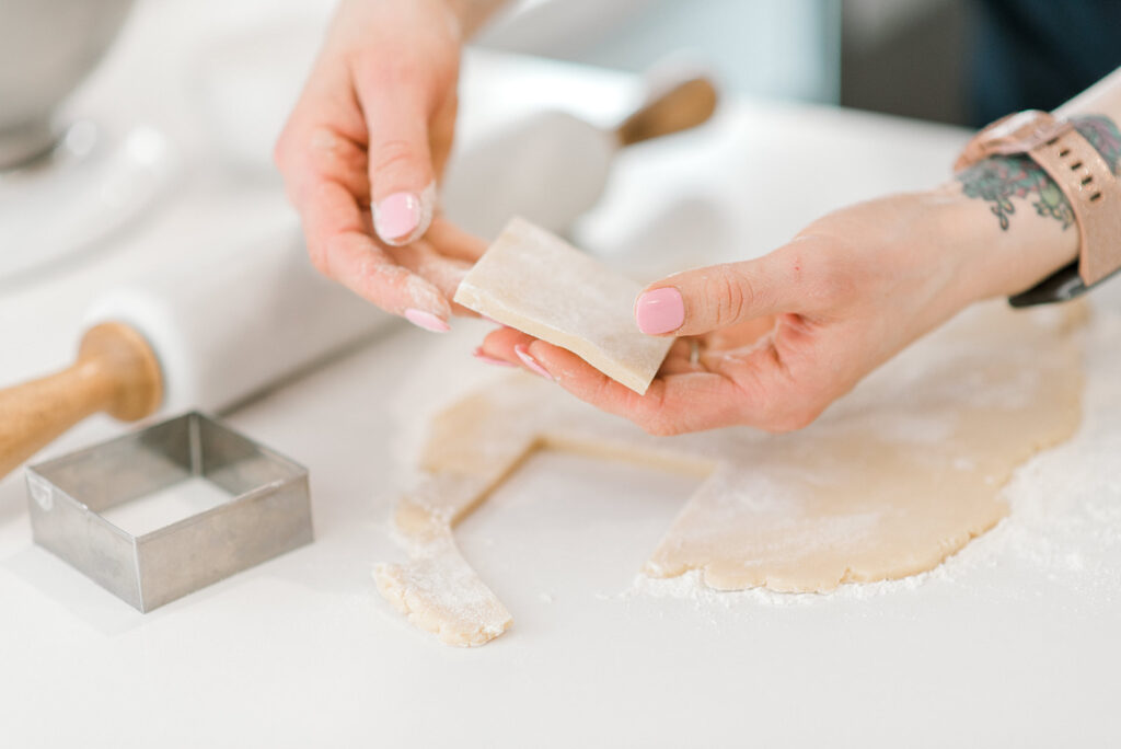 A baker's hands cut sugar cookies out of cookie dough during a small business photography branding session