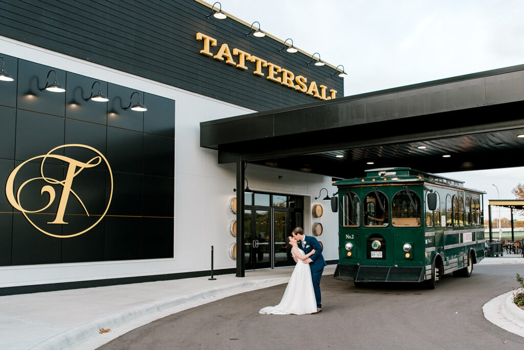 A bride and groom kiss in front of Tattersall Distilling in River Falls, WI