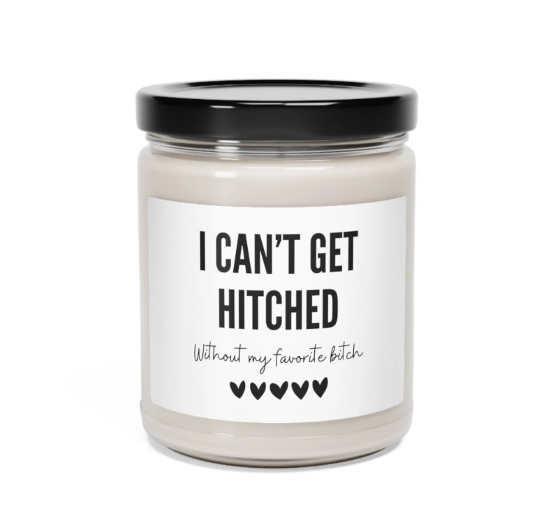 A soy wax candle in pink tissue paper.  The candle is a bridesmaid gift. The label reads "I Can't Get Hitched without my favorite bitch"