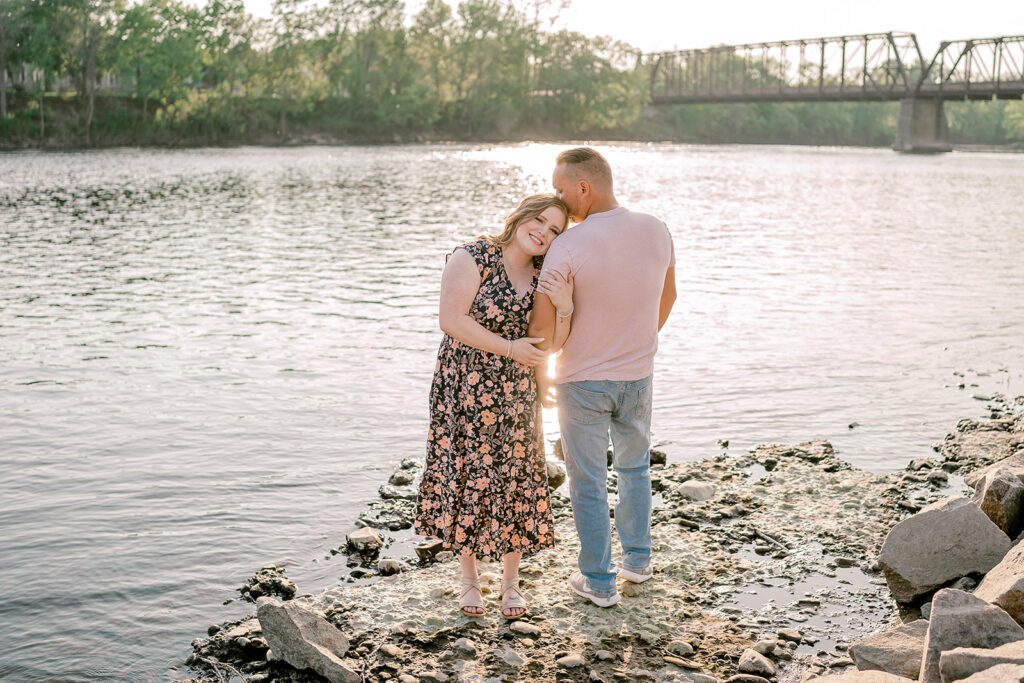 engaged couple embracing one another at the riverfront at phoenix park