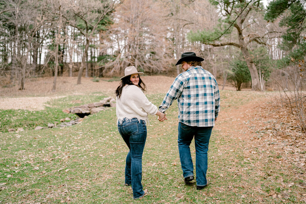 couple walking hand in hand at rod and gun park during their engagement session