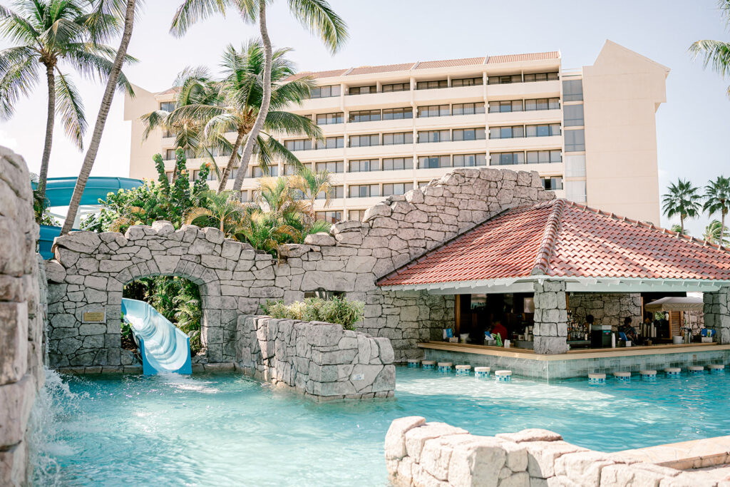 A water slide and pool bar are surrounded by Palm Trees at the Hyatt Regency in Aruba