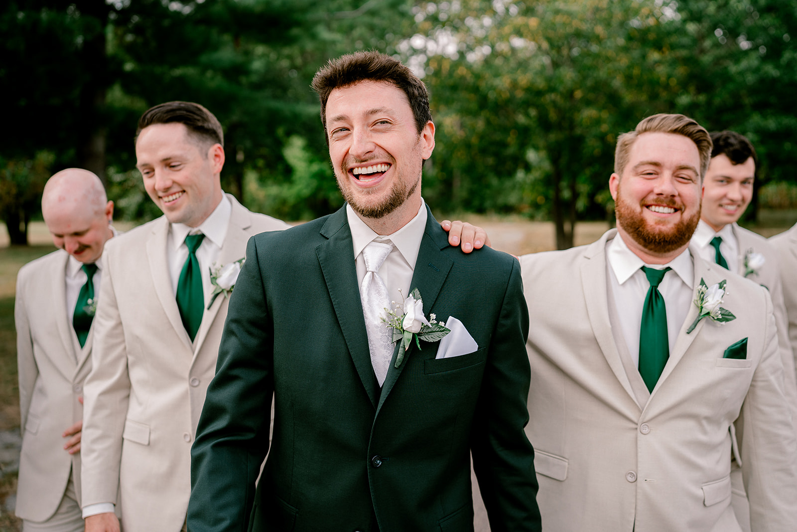 Groom in Green Suit walking with groomsmen in tan suits