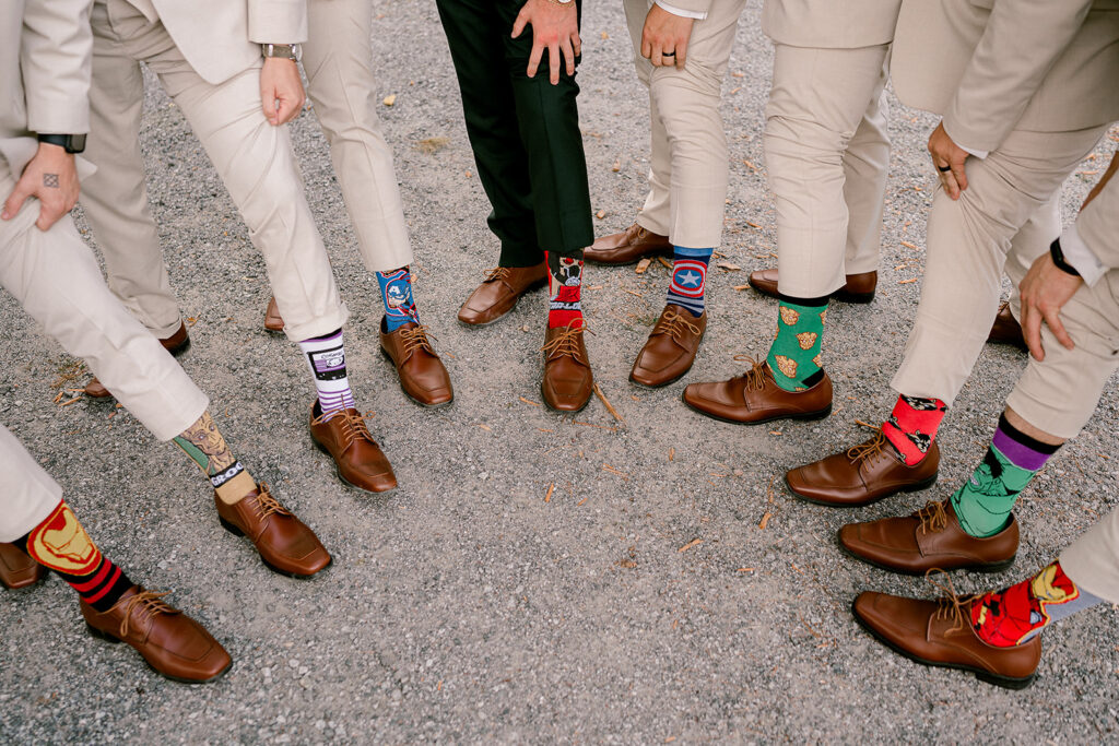 10 men hold their feet in a half circle and showing off coordinating Marvel Superhero socks. Groomsmen Gift Ideas. 